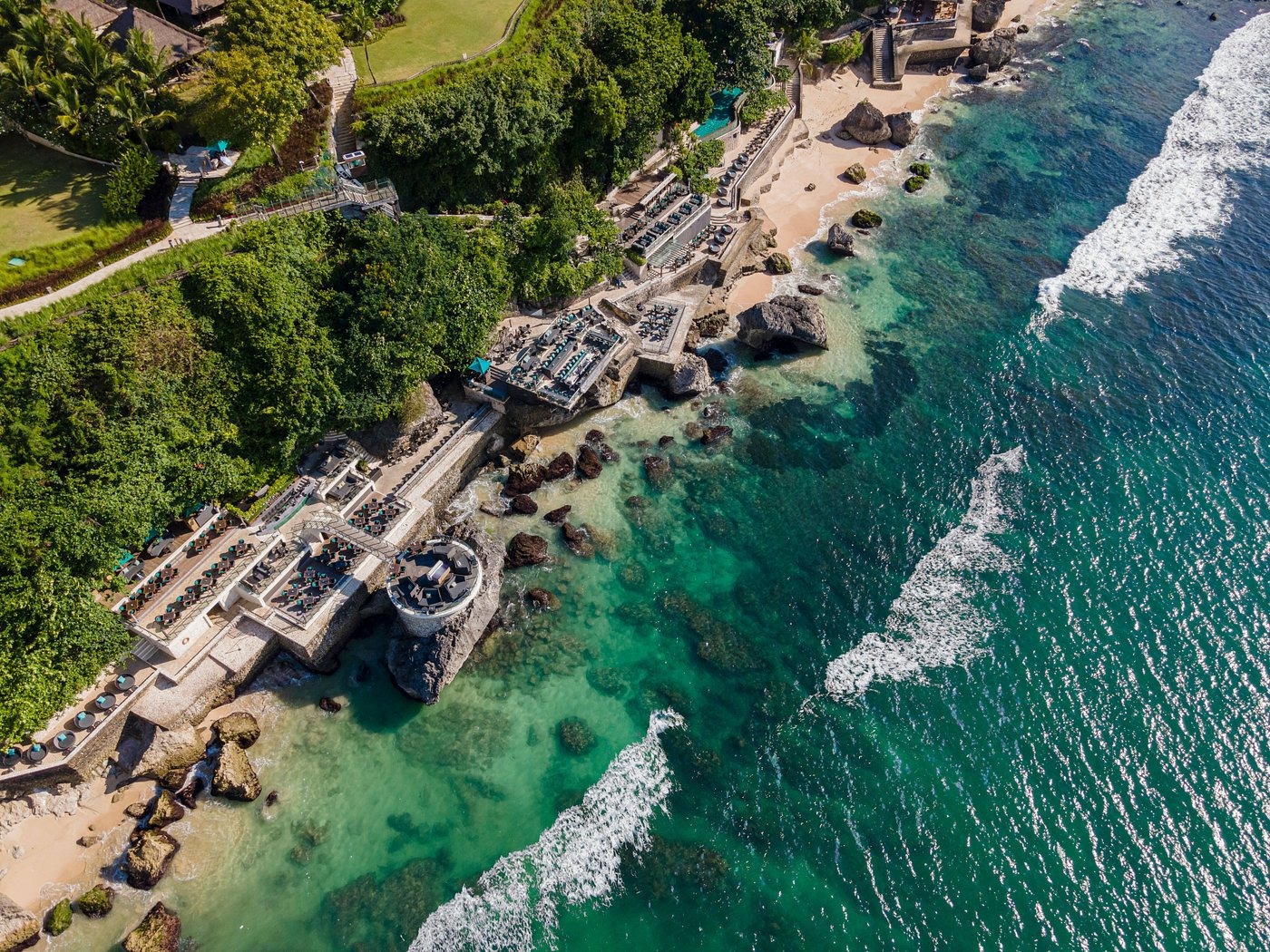 A stunning aerial view of a luxury beachfront resort surrounded by lush greenery and turquoise waters.